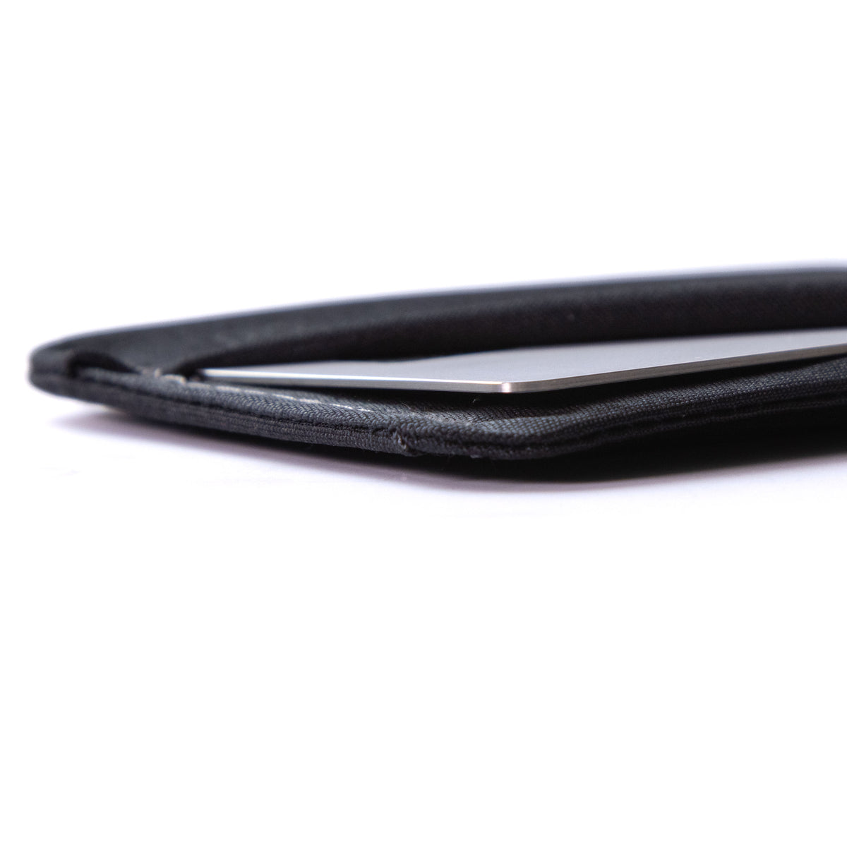 Close-up of a black minimalist card wallets holding a slim silver card, photographed on a clean white background. all-groups
