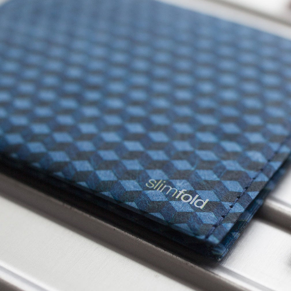 SlimFold cardholder wallet with a blue cube pattern, shown on a metallic surface.