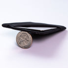 A black fabric minimalist wallet shown on a white background with a US quarter coin in front for scale. all-groups